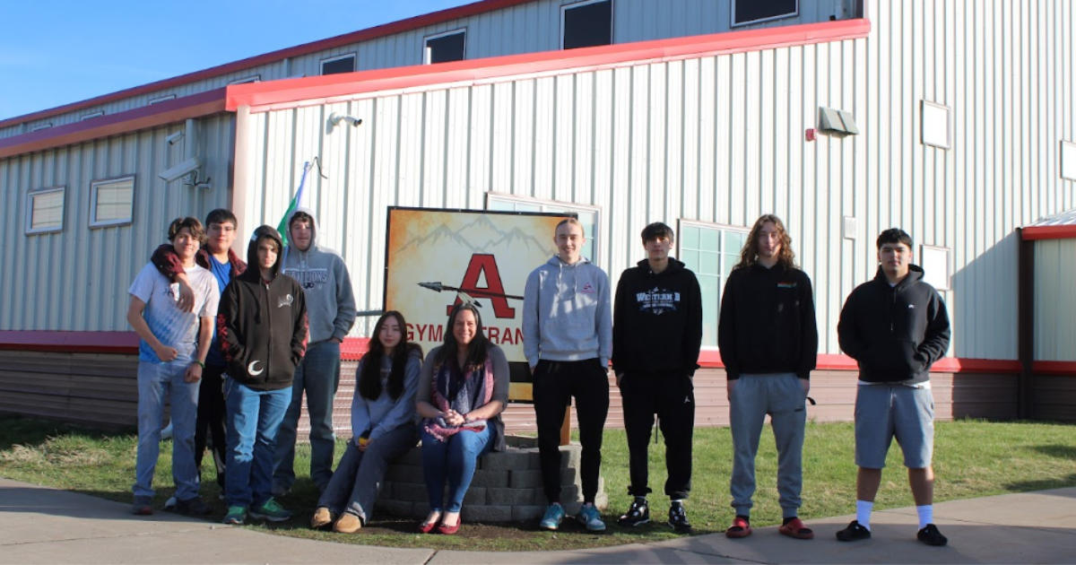 Students in the Arlee EAGLES club stand in front of their school sign